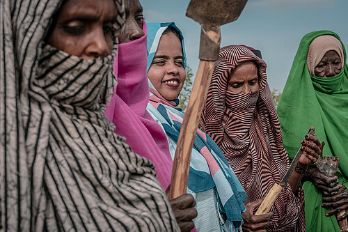 Four women in Sudan, holding agricultural tools